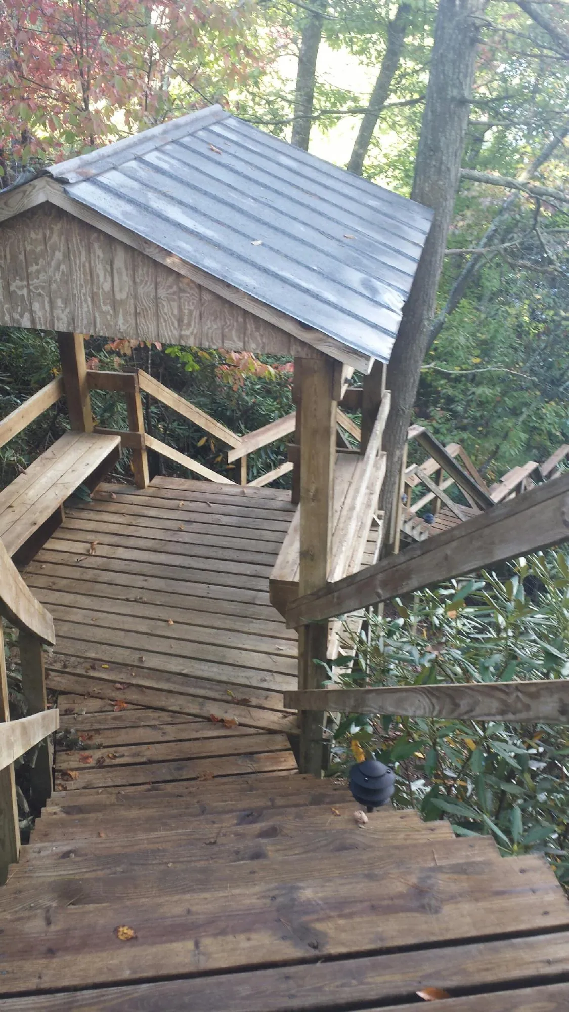 Metal roofed shelter over wooden steps on a wooded walkway — Skylight Repair & Installation work by our crew in Alexis